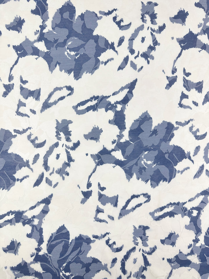 The Deluxe Print - Blue Flora - 150cm from Super Cheap Fabrics features a textured, painterly pattern of abstract blue floral shapes on white polyester, perfect for lightweight dress accessories with its organic overlapping motifs.