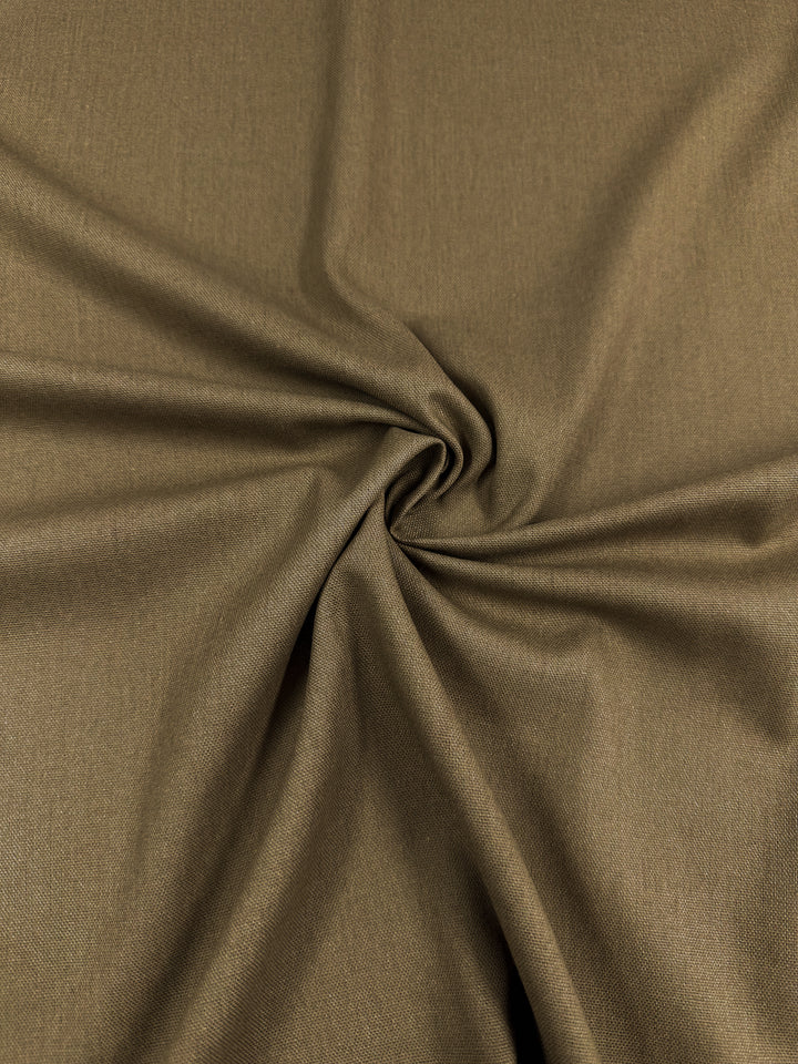 A close-up of Super Cheap Fabrics' Linen Blend - Cocha Mocha - 137cm with a smooth texture. The fabric is gathered and twisted at the center, creating a spiral pattern with soft folds radiating outward.