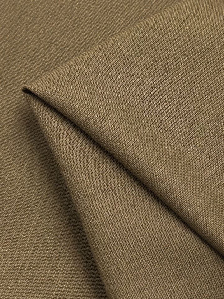 A close-up of a folded piece of Super Cheap Fabrics' Linen Blend - Cocha Mocha - 137cm, showcasing its texture and weave. The lightweight linen appears to be tightly woven, with a smooth surface that reflects light subtly, highlighting the quality and detail of the material.