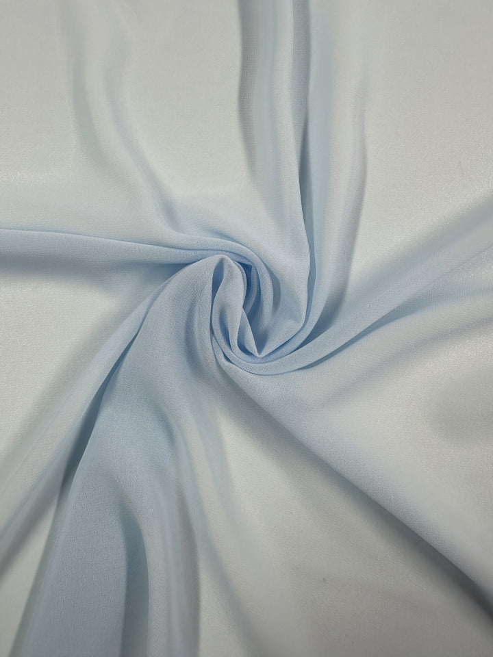 The Hi-Multi Chiffon in Powder Blue from Super Cheap Fabrics features a creamy white look with a subtle sheen. It's gathered and twisted to form a spiral pattern on lightweight, soft, and flexible 150cm wide fabric, creating gentle shadows and highlights.