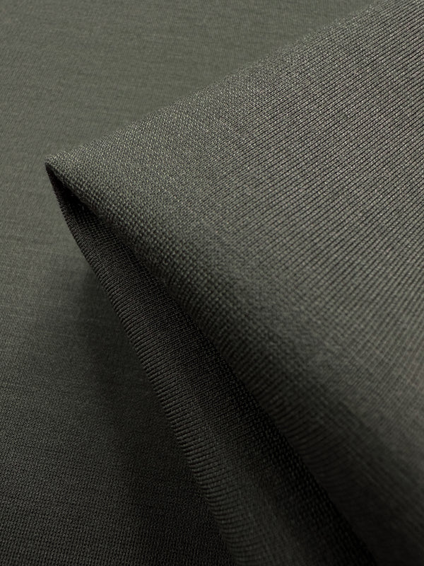 Close-up of folded Ponte De Roma - Deep Depths fabric, sourced from Australia by Super Cheap Fabrics, featuring a smooth and textured dark green surface. Under light, it appears soft, slightly reflective, and offers 4-way stretch for enhanced comfort. Width: 155cm.