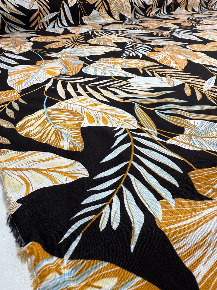 Super Cheap Fabrics’ Bamboo Rayon - Tropic Gold - 150cm features a lightweight fabric with bold gold, white, and light blue tropical leaves on black—perfect for beginner-friendly sewing projects.