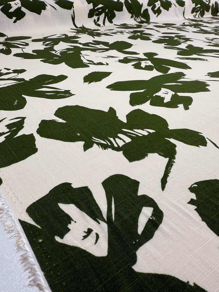 A close-up of Super Cheap Fabrics' Bamboo Rayon - Olive Bloom (150cm): a lightweight, beginner-friendly fabric in cream with bold, dark green abstract floral and face-like designs.