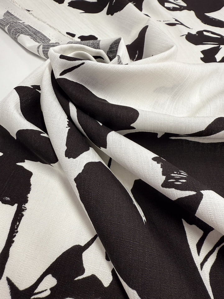 A close-up of Super Cheap Fabrics’ Bamboo Rayon - Jet Bloom (150cm), featuring lightweight fabric with bold abstract black floral prints, draped to highlight its soft texture—perfect for beginner-friendly sewing projects.