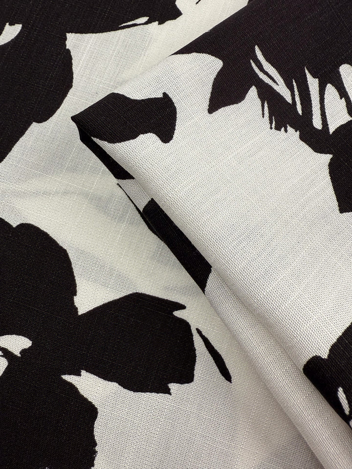 A close-up of Super Cheap Fabrics’ Bamboo Rayon - Jet Bloom (150cm) shows its lightweight feel and bold black-and-white abstract floral print, with visible weave—ideal for beginner-friendly sewing projects.