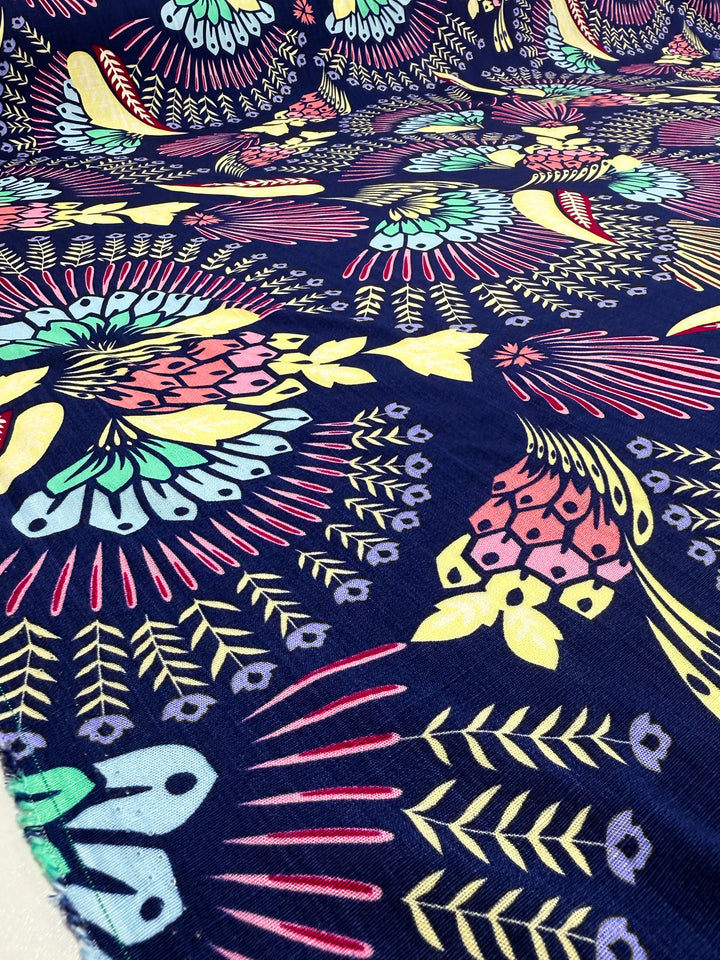 A close-up of vibrant geometric floral and bird patterns in pink, yellow, green, and blue on Super Cheap Fabrics' Bamboo Rayon - Midnight Carnival (150cm), ideal for beginner sewing projects.