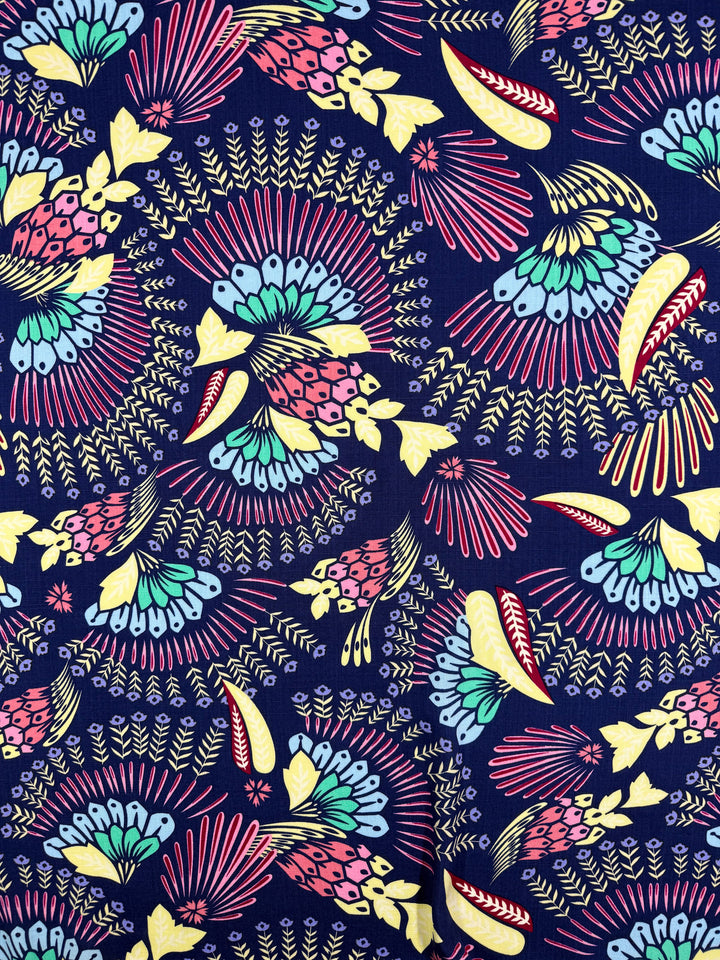 Bamboo Rayon - Midnight Carnival by Super Cheap Fabrics features colorful floral and abstract leaves in pink, yellow, turquoise, and light blue on a dark blue background—ideal for beginner-friendly sewing projects. Width: 150cm.