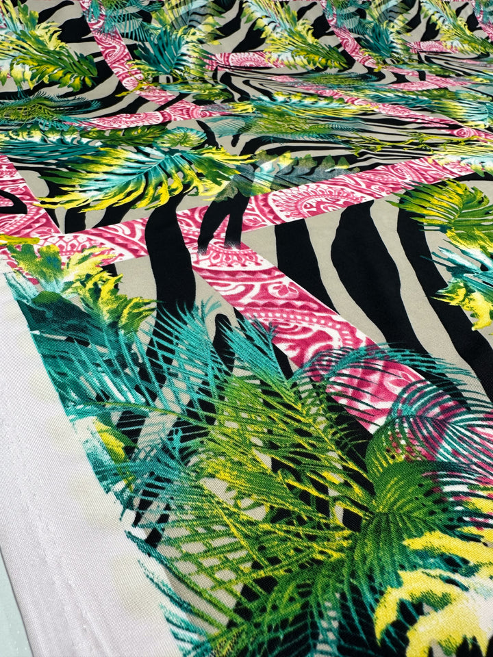 The Printed Lycra - Jungle Frame by Super Cheap Fabrics offers a dynamic blend of zebra stripes, green and yellow palm leaves, and pink paisley. Made from polyester/spandex, it features a breathable two-way stretch for comfort and flexibility, all within its vibrant 145cm design.