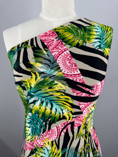 A mannequin displays Super Cheap Fabrics' Printed Lycra - Jungle Frame (145cm), showcasing a vibrant Polyester/Spandex blend with green/yellow leaves, pink circles, and black-and-white zebra stripes in a botanical and geometric print, creating an asymmetrical look.