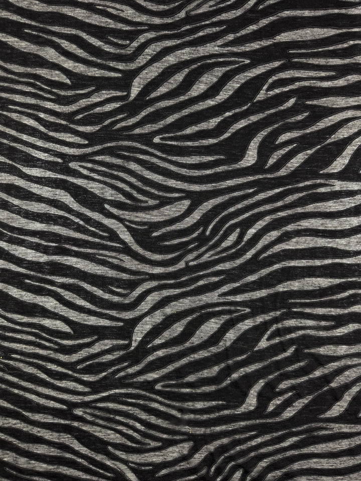 The Burnout Jersey - Zebra from Super Cheap Fabrics features irregular black stripes on a gray background, offering a bold and dynamic visual effect. This fabric is 160cm wide.