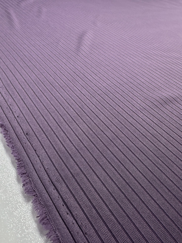 Close-up of Super Cheap Fabrics' Rib Knit - Grape Compote, a medium weight fabric with horizontal lines and detailed texture showing small peaks and valleys. The slightly frayed left edge suggests its unfinished side, typical of these textured knits. Width: 170cm.