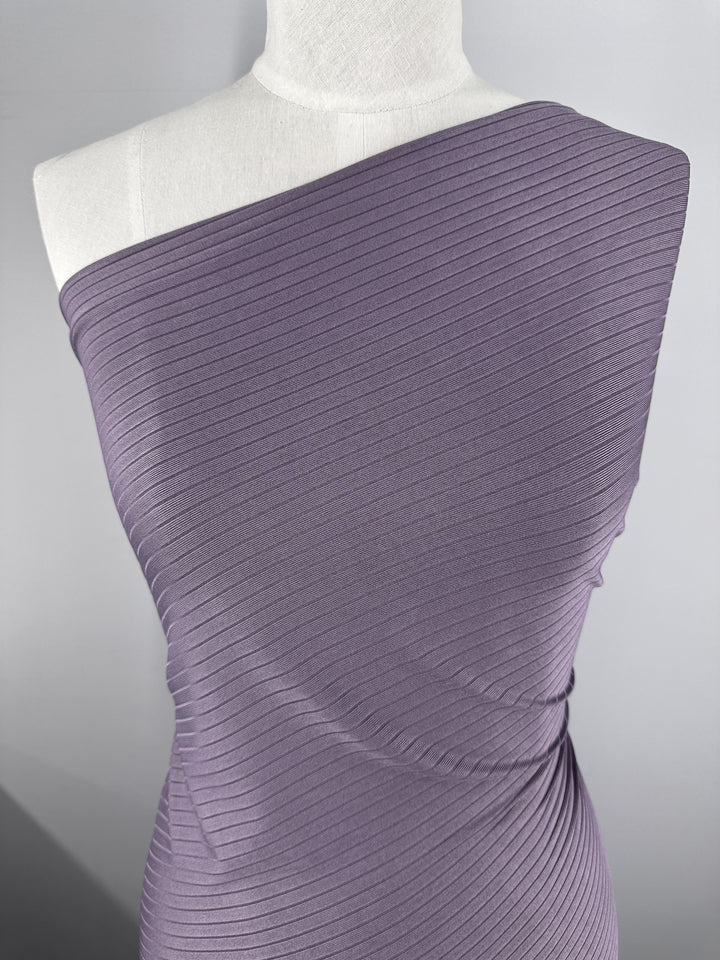 Wrapped snugly on a mannequin, the Rib Knit - Grape Compote from Super Cheap Fabrics showcases its medium weight, one-shoulder drape. The fabric's texture and slight sheen are enhanced by subtle folds that accentuate the mannequin's contours.