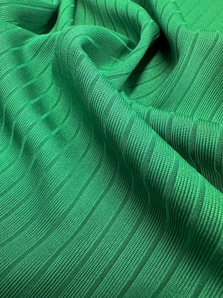 Close-up of Super Cheap Fabrics' Rib Knit in Abundant Green (177cm), showcasing medium weight fabric with textured vertical lines, softly gathered for gentle folds and shadows.