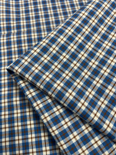 The Shirting - Ralph - 150cm from Super Cheap Fabrics features a lightweight polyester material adorned with a checkered pattern of blue, brown, and white squares. Its crisp look is highlighted by the precisely aligned grid design, making it versatile for various uses.