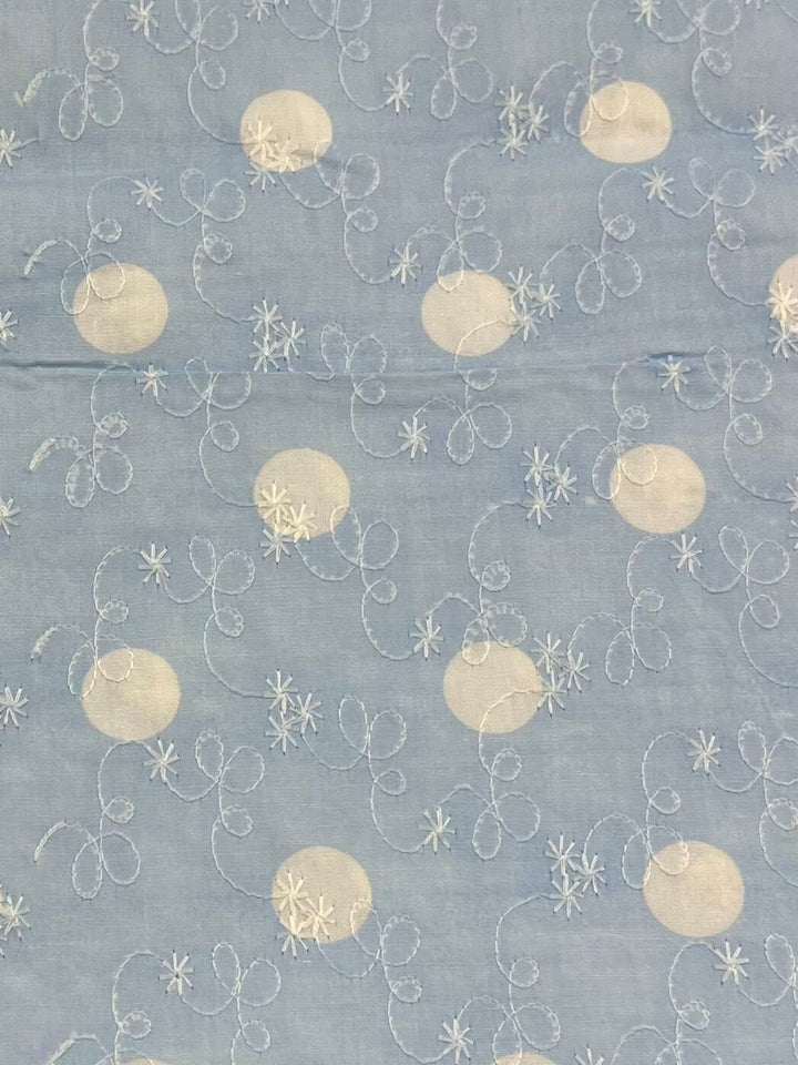 Introducing the "Embroidered Printed Cotton - Baby Blue - 112cm" by Super Cheap Fabrics, this fabric showcases a delicate pattern of white oval shapes and swirling lines against a light blue backdrop. The snowflake-like designs are subtly interwoven throughout, all crafted from natural cotton fibers, making it an excellent choice for creating elegant clothing and household items.