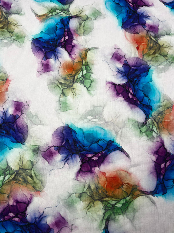 Experience the dynamic and fluid elegance of the Designer Cotton - Azurine by Super Cheap Fabrics. This luxurious fabric features a vibrant abstract pattern of swirling shapes in blue, purple, green, and orange against a pristine white background, reminiscent of watercolor brush strokes. Ideal for high-end sewing projects.