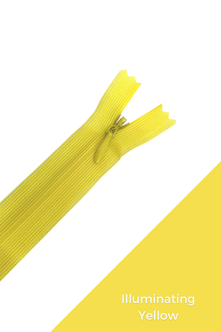 An image displays a yellow zipper, partially unzipped, against a white background. In the bottom right corner of the image, there is a yellow diagonal stripe with "Illuminating Yellow" written in white lowercase letters. This durable and elegant zipper, part of the Invisible Zip - 30cm - Yellows & Oranges collection from Super Cheap Fabrics, complements any design perfectly.