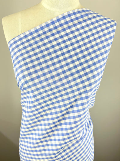 A dressmaker's mannequin draped with *Cotton - Frozen Gingham - 145cm* from *Super Cheap Fabrics*. The lightweight 100% cotton fabric is arranged diagonally across the chest, showcasing the classic checkered pattern. The background is a neutral light grey, drawing attention to the fabric's details.