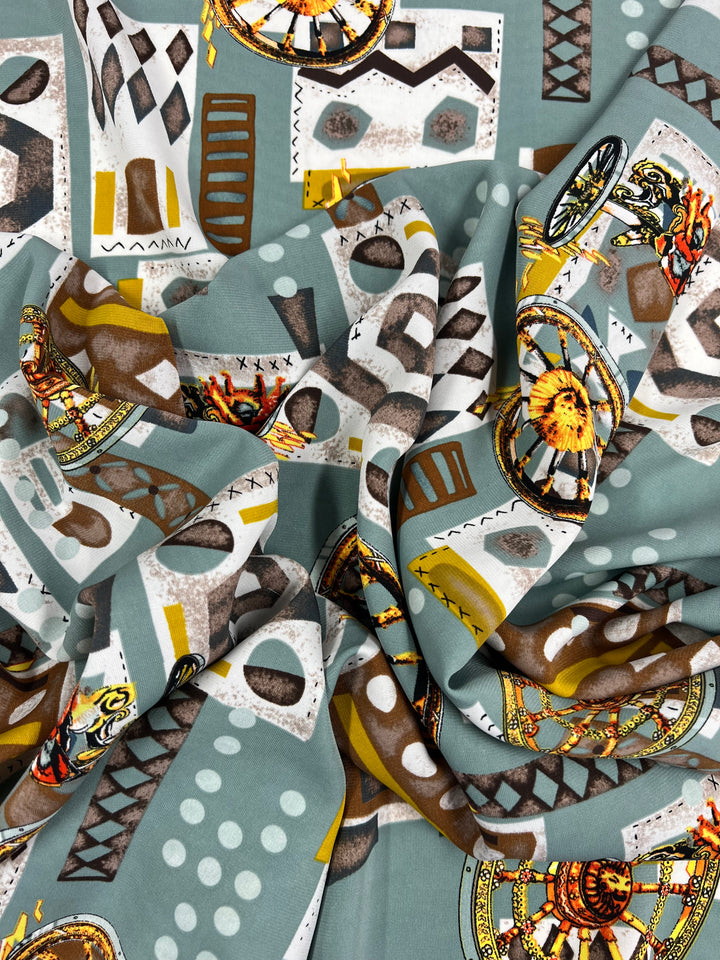 A versatile fabric featuring a vibrant, abstract pattern with geometric shapes and motifs. The design includes triangles, circles, and rectangles in various colors like white, gray, yellow, and brown, along with detailed illustrations of wheels, possibly from traditional vehicles is available in Deluxe Print - Medieval - 150cm by Super Cheap Fabrics.