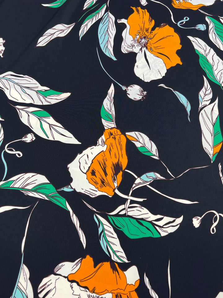 A versatile fabric with a dark background is adorned with a vibrant floral pattern featuring large orange and white flowers, green leaves, and flowing lines, creating an intricate and lively design. Deluxe Print - Marigold Comic - 150cm by Super Cheap Fabrics stands out among designer fabrics for its bold aesthetic appeal.