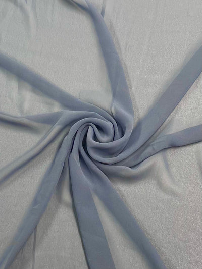 A piece of Hi-Multi Chiffon - Flint Stone - 150cm from Super Cheap Fabrics is gathered and twisted into a spiral shape on a flat surface. The lightweight polyester material appears soft and semi-transparent, showcasing delicate folds and a gentle sheen.