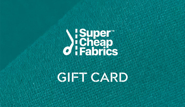 A Super Cheap Fabrics Gift Vouchers with a textured teal fabric background. The text reads "Super Cheap Fabrics" at the top, with a stylized needle and thread logo. Below, the text "GIFT CARD" is prominently displayed in white capital letters—a perfect treat for any sewing enthusiast to redeem online.
